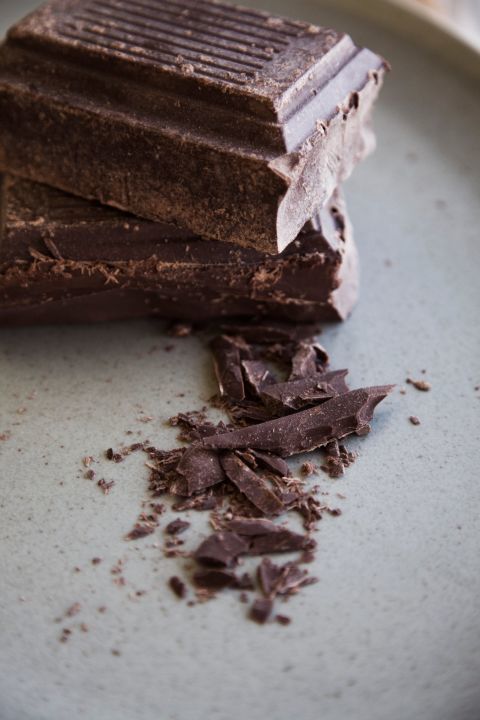 Thanh sô cô la đen nằm trên đĩa, với một số mảnh vụn xung quanh. Thực phẩm giảm stress như sô cô la đen là lựa chọn tốt cho những ai đang đối mặt với căng thẳng và áp lực công việc.