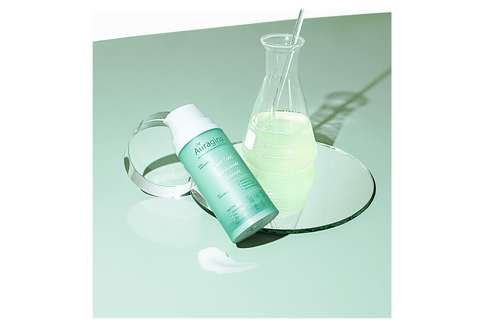 Gel dưỡng ẩm ngừa mụn, giảm thâm The Auragins Skin Rescue Brightening Gel Cream 100ml trên bề mặt gương với một bình thủy tinh chứa dung dịch màu xanh nhạt, thể hiện khả năng dưỡng ẩm và cải thiện sắc da.
