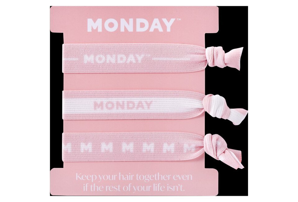 Thun cột tóc Monday với ba dây buộc tóc màu hồng trên nền thẻ trang trí. Thiết kế với chữ 'MONDAY' và câu slogan 'Keep your hair together even if the rest of your life isn't.'