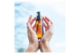 Dầu Dưỡng Tóc La CASTA Aromaesthe Hair Oil Phục Hồi và Mềm Mượt Tóc 80ml được cầm trên tay với nền trời xanh, thể hiện vẻ đẹp tự nhiên và sự chăm sóc tóc hoàn hảo.
