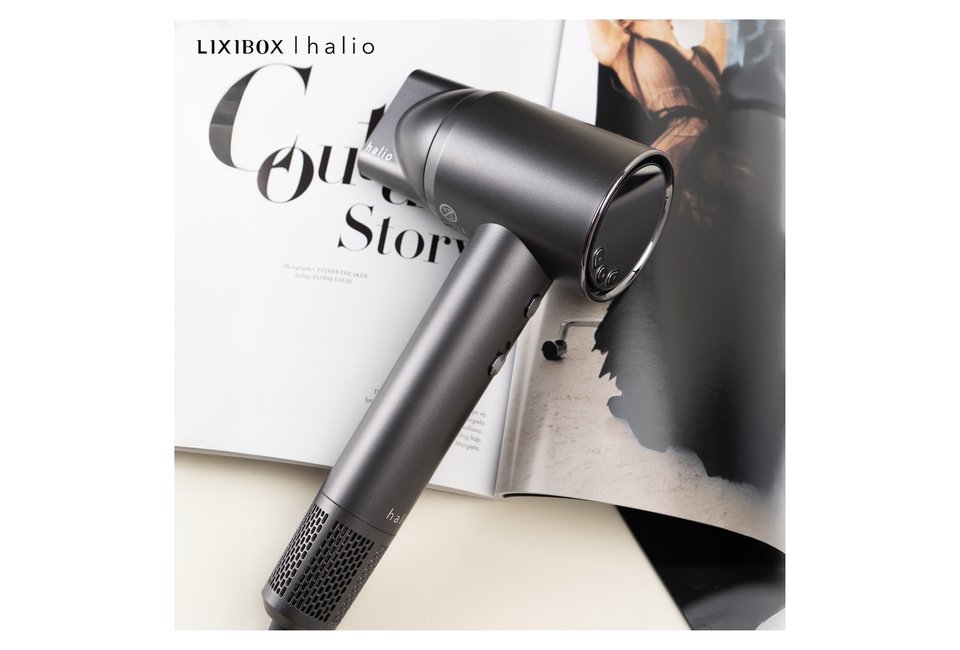 Máy Sấy Tóc Ion Âm Halio Hypersonic Hair Dryer Space Grey với thiết kế hiện đại, nằm cạnh một tờ tạp chí thời trang, tôn lên vẻ đẹp sang trọng cho không gian sử dụng.