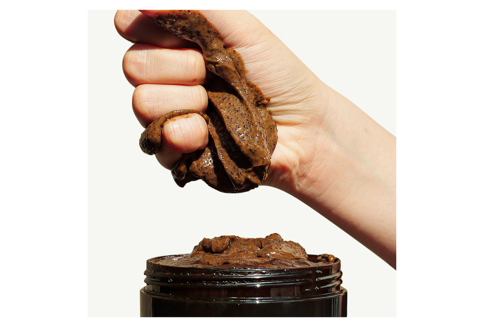 CoBa’s Daughter Body Exfoliator 300gr, a rich, textured scrub being squeezed from a black jar, highlighting its natural ingredients ideal for skin smoothing and rejuvenation.