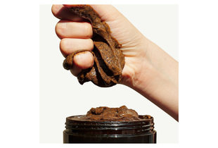 CoBa’s Daughter Body Exfoliator 300gr, a rich, textured scrub being squeezed from a black jar, highlighting its natural ingredients ideal for skin smoothing and rejuvenation.