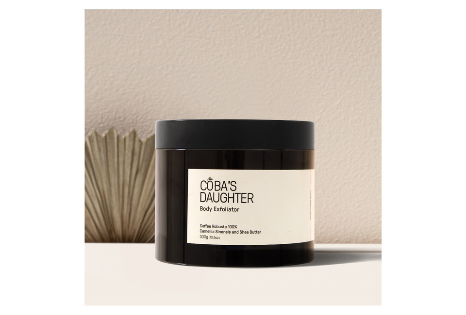CoBa’s Daughter Body Exfoliator 300gr in a dark jar, featuring a label that highlights key ingredients: Coffee Robusta 100%, Camellia Sinensis, and Shea Butter, displayed against a neutral background for an elegant presentation.
