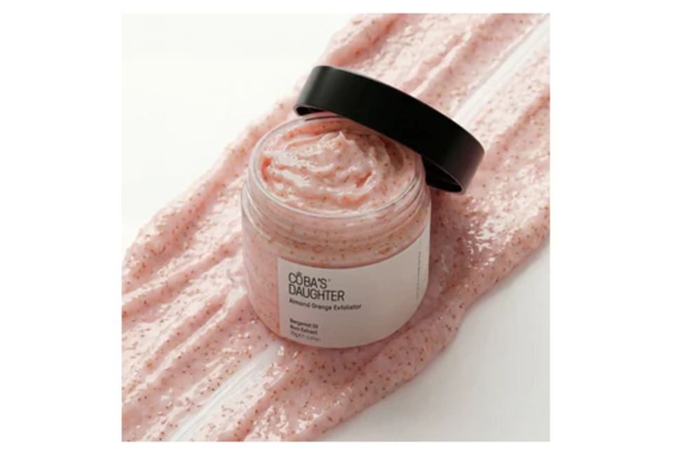 Bộ chăm sóc cơ thể tẩy tế bào chết & dưỡng ẩm cho da - CoBa's Daughter Exfoliate & Nourish Bodycare Set với sản phẩm tẩy tế bào chết có màu hồng nhạt, nằm trên bề mặt kem lấp lánh, cung cấp ẩm và làm mềm da.